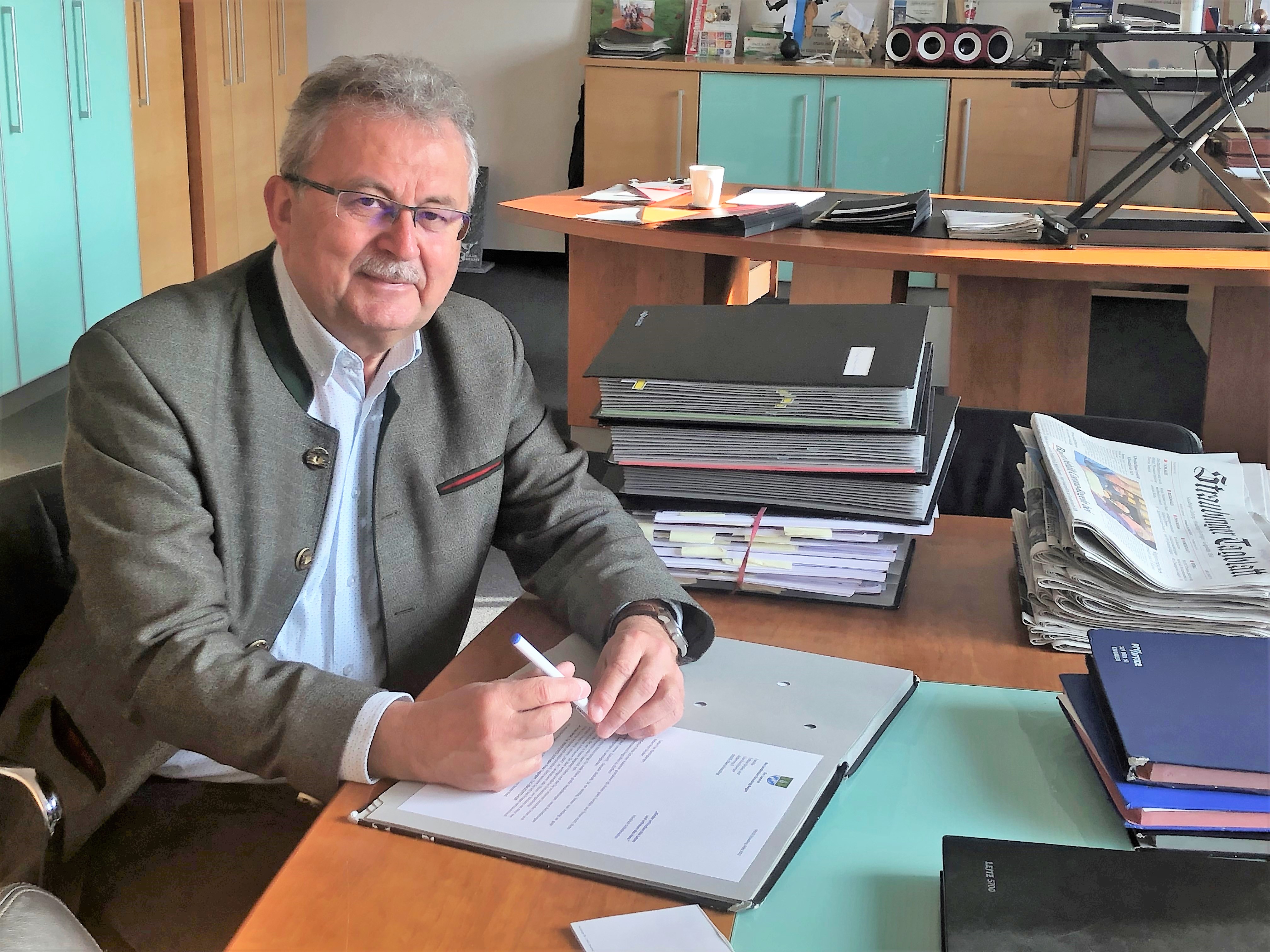 Landrat Josef Laumer in seinem Büro am Schreibtisch umgeben von Unterlagen.