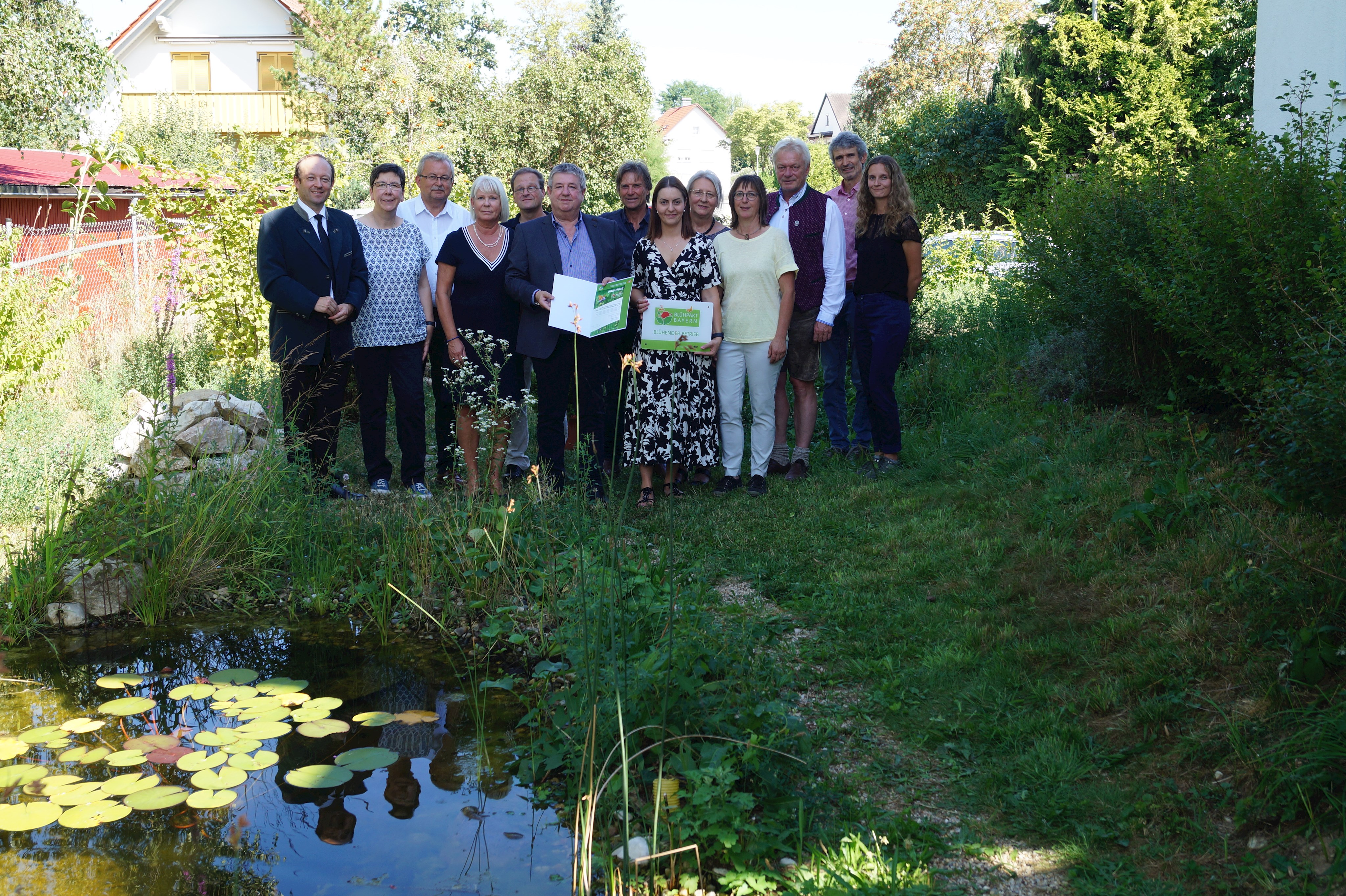 Dieter Hantke und Mitarbeiterin Christina Rösler (vorne mitte) mit der Auszeichnung im Naturgarten gemeinsam mit den Ehrengästen, unter anderem Straßkirchens Bürgermeister Dr. Christian Hirtreier, Dagmar Schmitt vom Bayerischen Staatsministerium für Umwelt und Verbraucherschutz, Landrat Josef Laumer (von links), Landschaftsarchitekt Anton Robl (Siebter von links) und MdB Alois Rainer (Dritter von rechts).