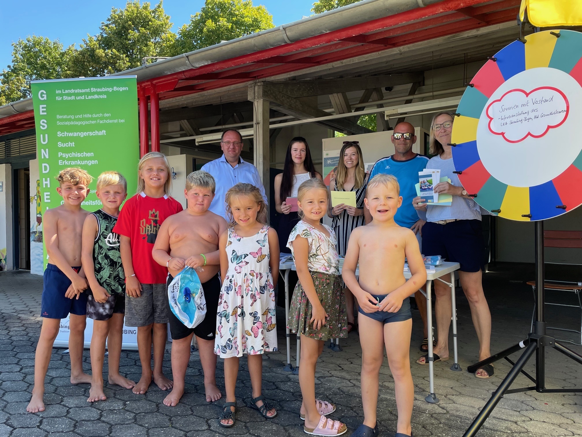 Bürgermeister Herbert Lichtinger, Praktikantin Janine Miedaner, Sozialpädagogin Stefanie Jakob, Bademeister Martin Schmidt, Sozialpädagogin Alexandra Jehle (hinten von links) mit kleinen Badegästen am Glücksrad im Freibad in Geiselhöring.