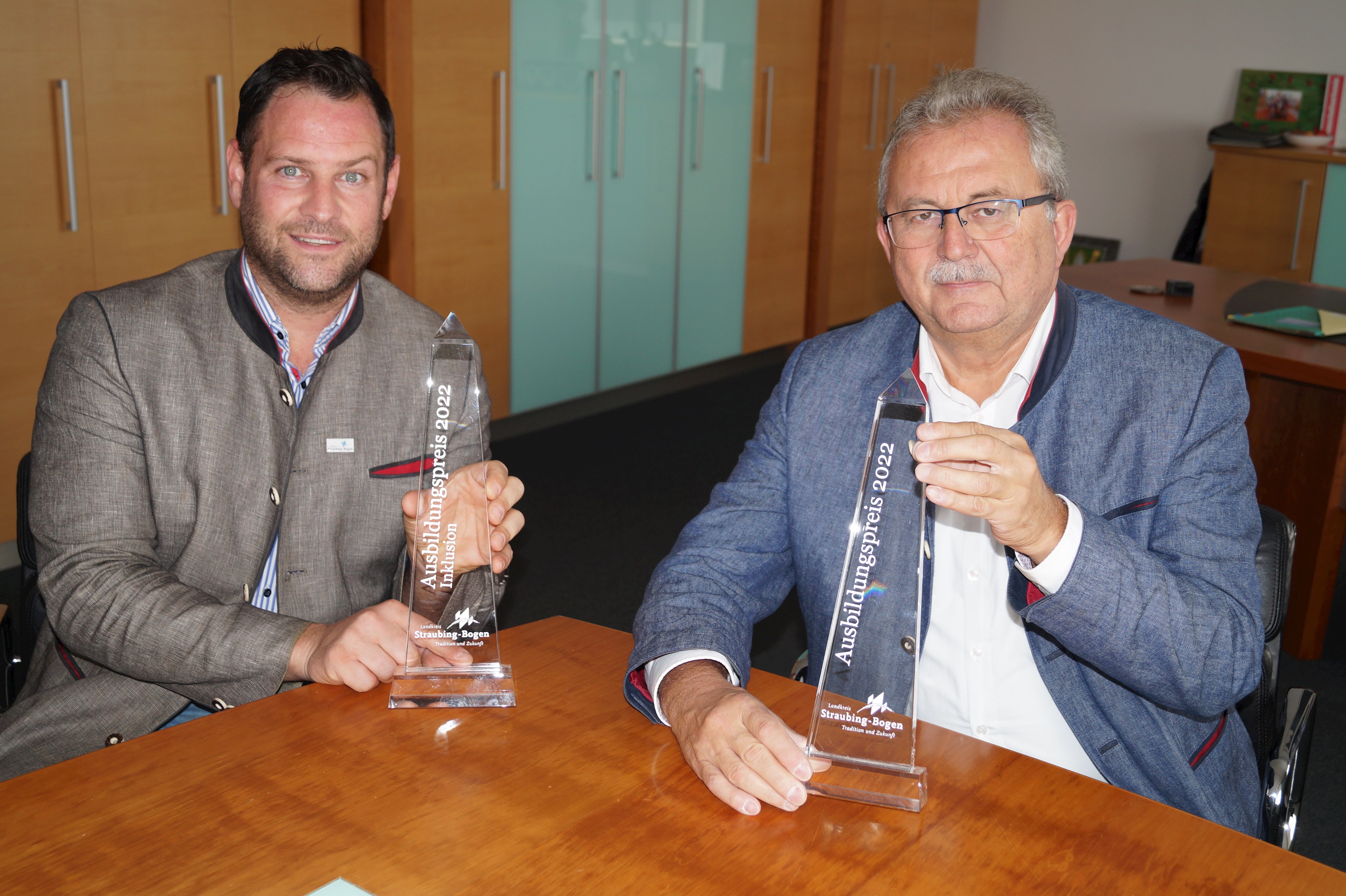 Martin Köck (links) und Josef Laumer präsentieren im Büro des Landrats die Preise für den Ausbildungspreis.