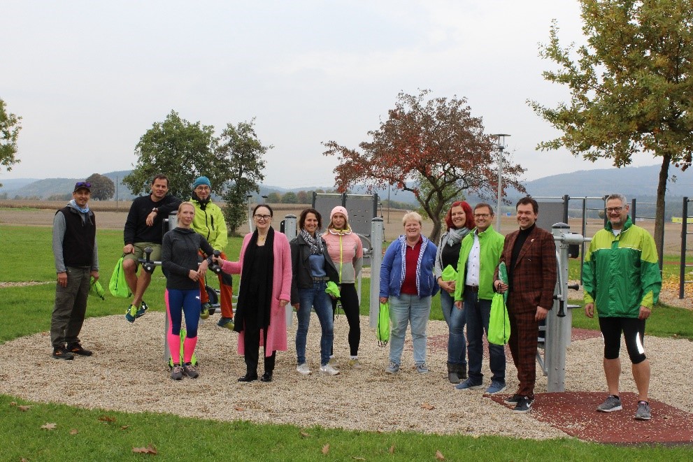 Josefine Hilmer (Geschäftsführerin des Regionalentwicklungsvereins, 5. von links), Mareike Richter (PX Sports Straubing, 7. von links),  Markus Schuirer (Teamleiter Prävention und Öffentlichkeitsarbeit AOK Straubing), Matthias Fischer (Bürgermeister Kirchroth), Georg Kagermeier (AOK-Direktor Straubing), Kathrin Haberl (Seniorenfachstelle Landkreis Straubing-Bogen, von rechts) stehen gemeinsam mit den ehrenamtlichen Akteuren vor der Schulung im Fitnessparcours an den Geräten.