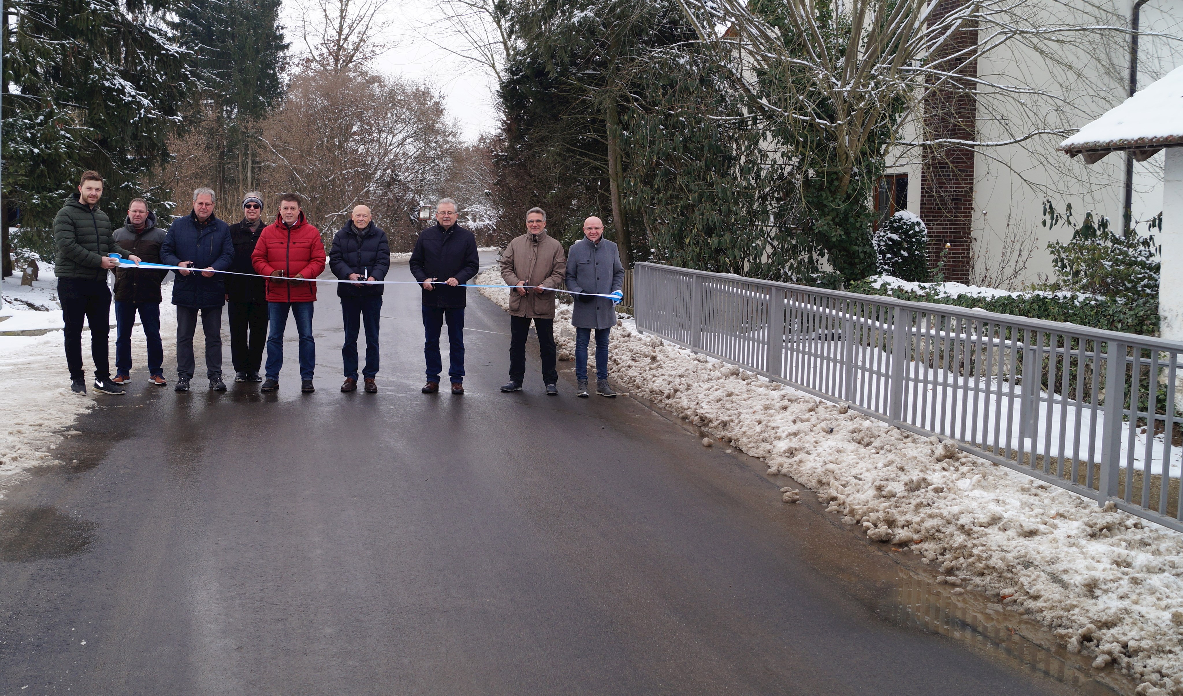 Landrat Josef Laumer (3. von rechts) und Bürgermeister Ewald Seifert (mitte) stehen bei der offiziellen Einweihung gemeinsam mit Pfarrer Dr. Maier und Vertretern der Verwaltung und der beteiligten Firmen auf der neuen Brücke.