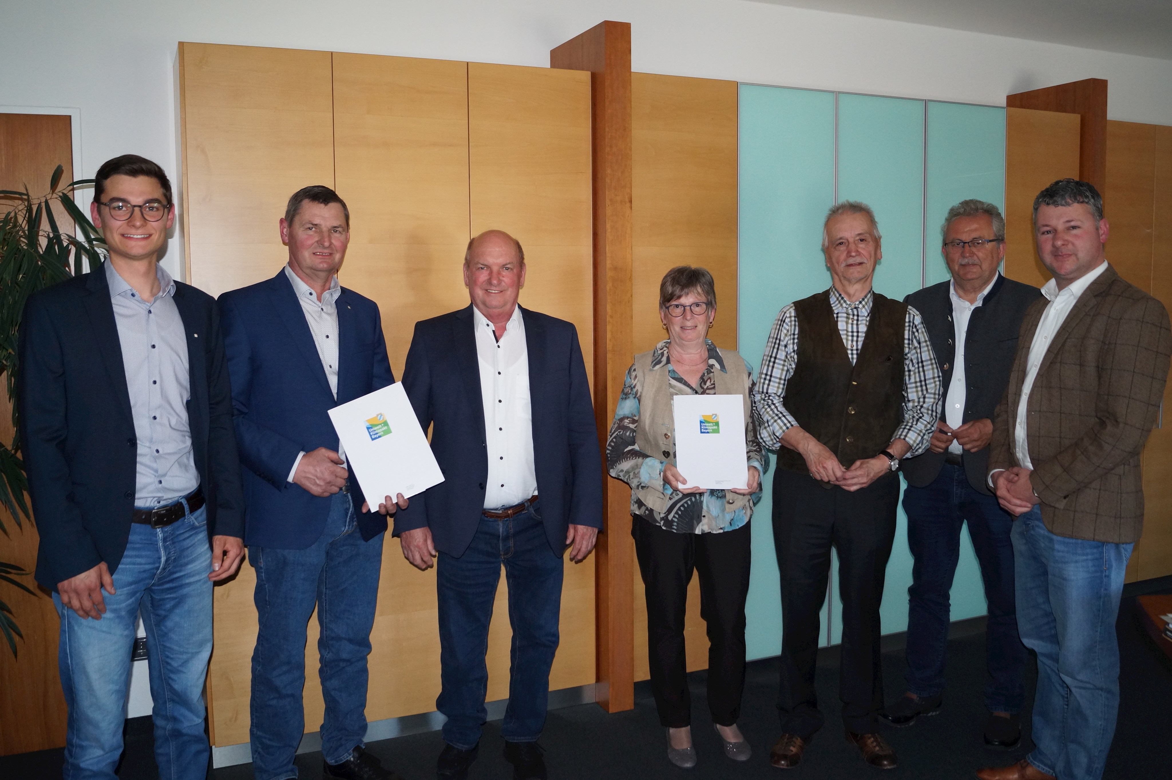 Johannes und Martin Haider, Leiblfings Bürgermeister Josef Moll, Irene und Burkhard Hübner, Landrat Josef Laumer, Neukirchens Bürgermeister Matthias Wallner (von links) stehen bei der Übergabe der Urkunden im Büro des Landrats.