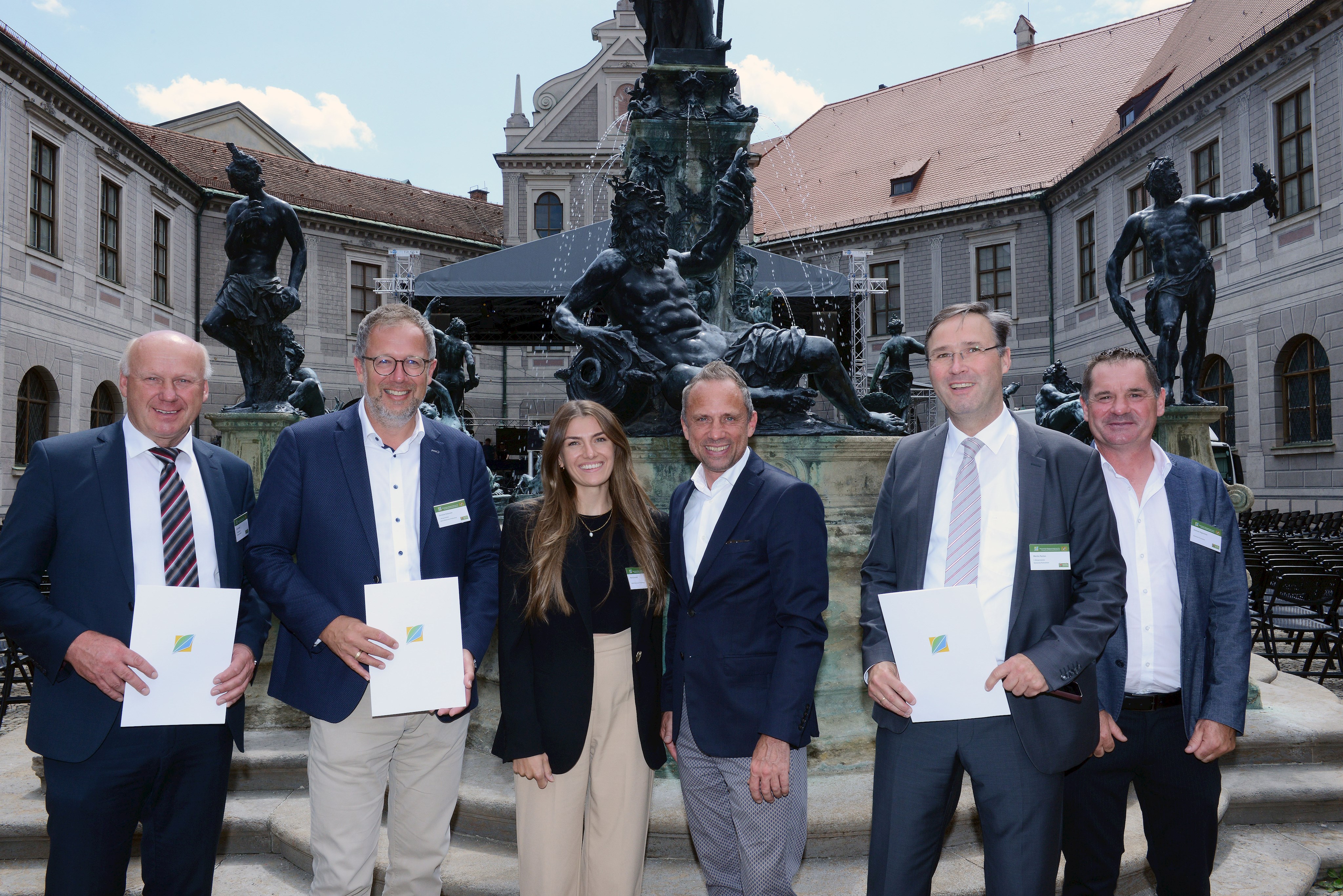 Bürgermeister Fritz Schötz (Haibach), Bürgermeister Christian Dobmeier (Mallersdorf-Pfaffenberg), Klimaschutzmanagerin Maria Schießl (Landkreis Straubing-Bogen), Bayerns Staatsminister für Umwelt und Verbraucherschutz Thorsten Glauber, Bürgermeister Martin Panten (Parkstetten) und Andreas Sagmeister (Gemeinde Parkstetten, von links) stehend nach der Verleihung vor der Residenz in München.