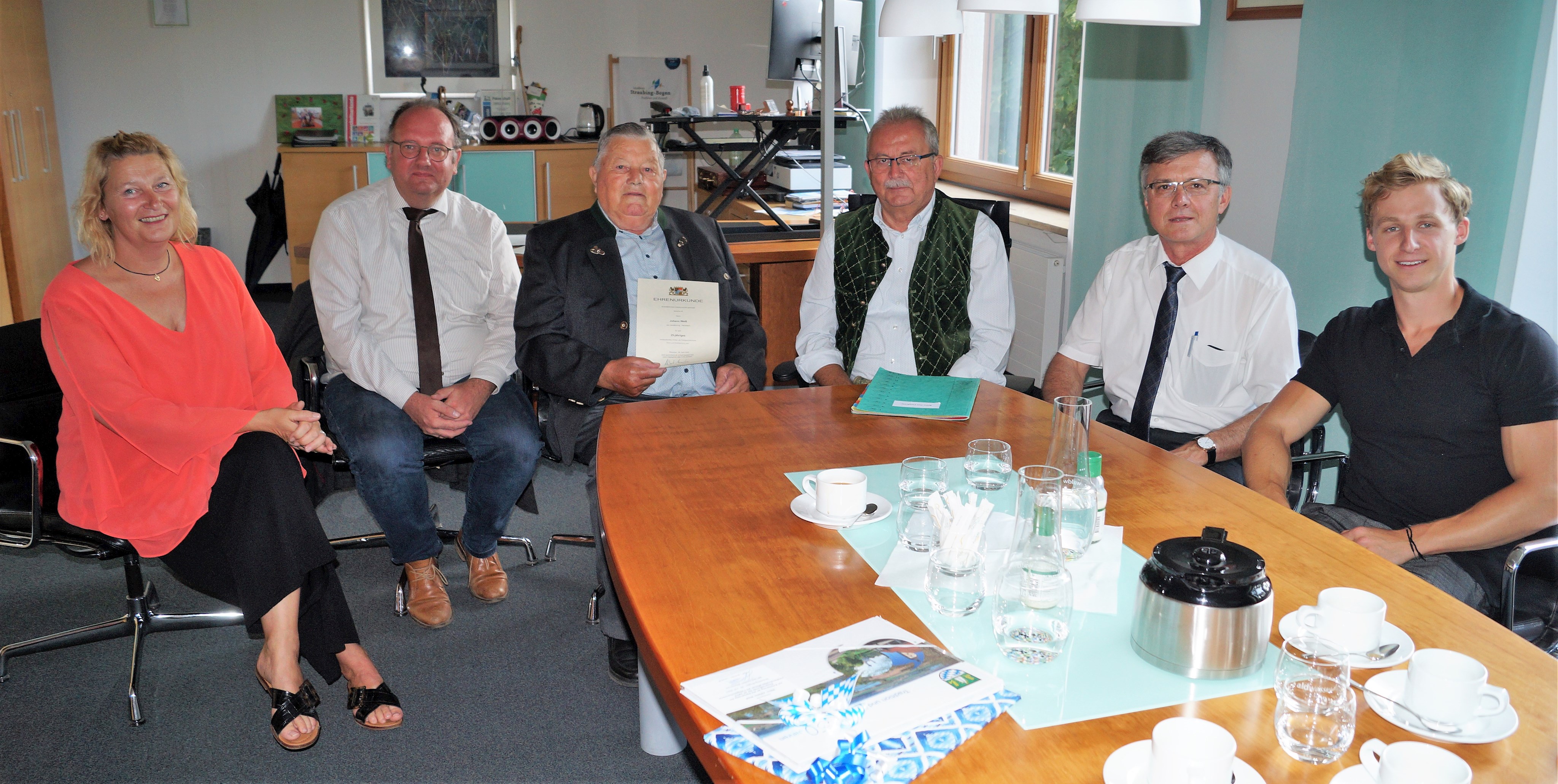 Sonja Mauser (Bauamt Stadt Geiselhöring), Geiselhörings Bürgermeister Herbert Lichtinger, Johann Weiß, Landrat Josef Laumer, Vermessungsdirektor Johann Lerchenberger gemeinsam mit einem Referendar seines Amtes sitzen nach der Ehrung im Büro des Landrats.