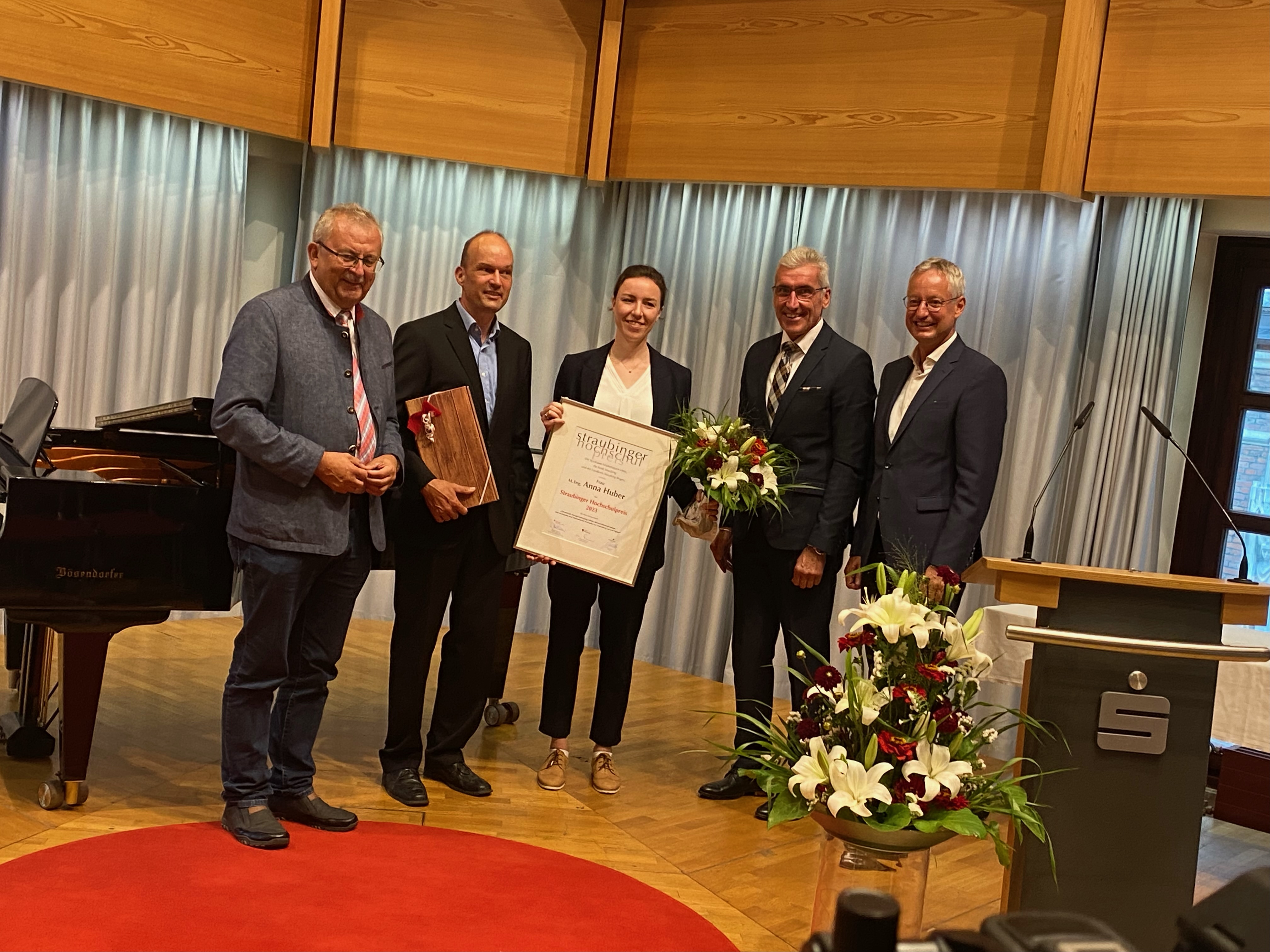 Landrat Josef Laumer, Laudator Prof. Dr. Josef Kainz, Preisträgerin Anna Huber, Walter Strohmaier (Vorstandsvorsitzender der Sparkasse Niederbayern-Mitte) und Oberbürgermeister Markus Pannermayr bei der Preisübergabe auf der Bühne.