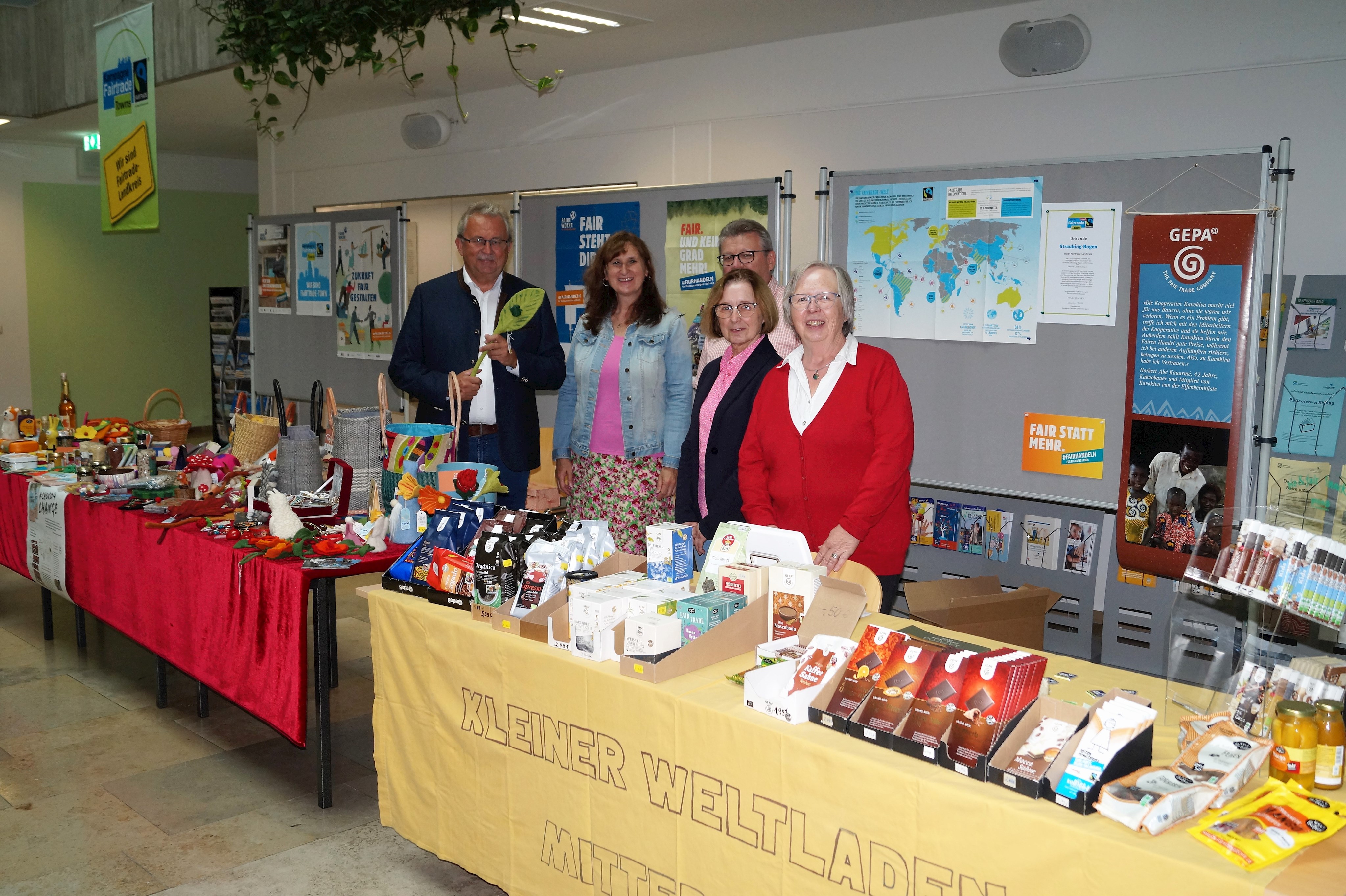 Mitglieder der Fairtrade-Steuerungsgruppe stehen gemeinsam mit Landrat Josef Laumer am Präsentations- und Verkaufsstand im Foyer des Landratsamtes.