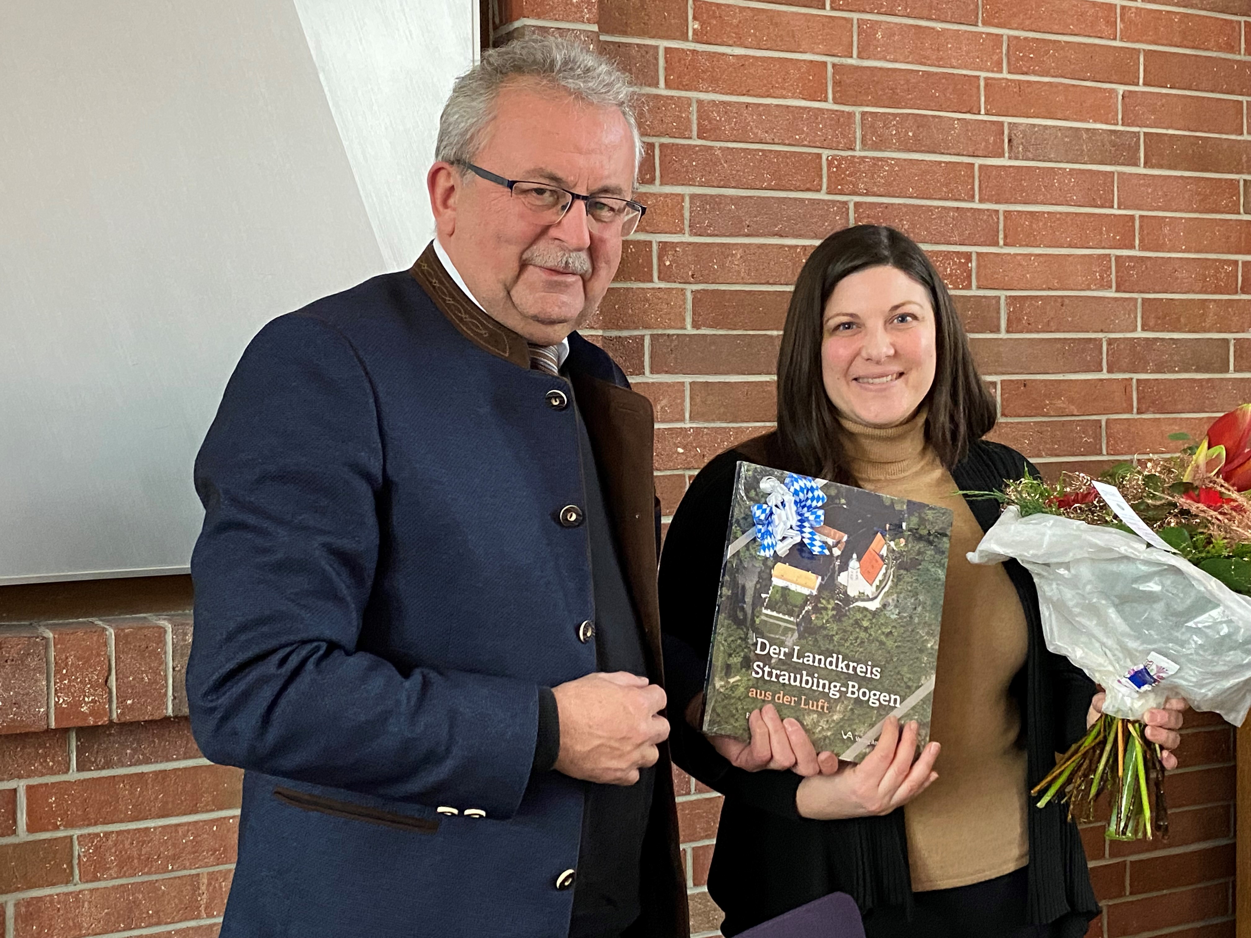 Landrat Josef Laumer verabschiedet Johanna Uekermann mit einem Blumenstrauß und einem Geschenk.