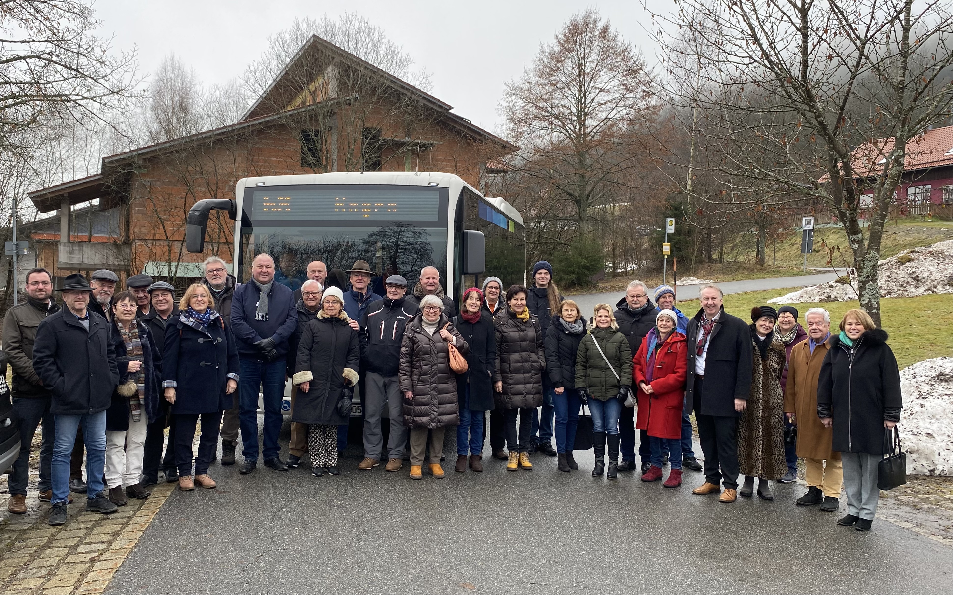 Die Ehrengäste stehen vor dem Bus an der Bushaltestelle Kurpark in St. Englmar.