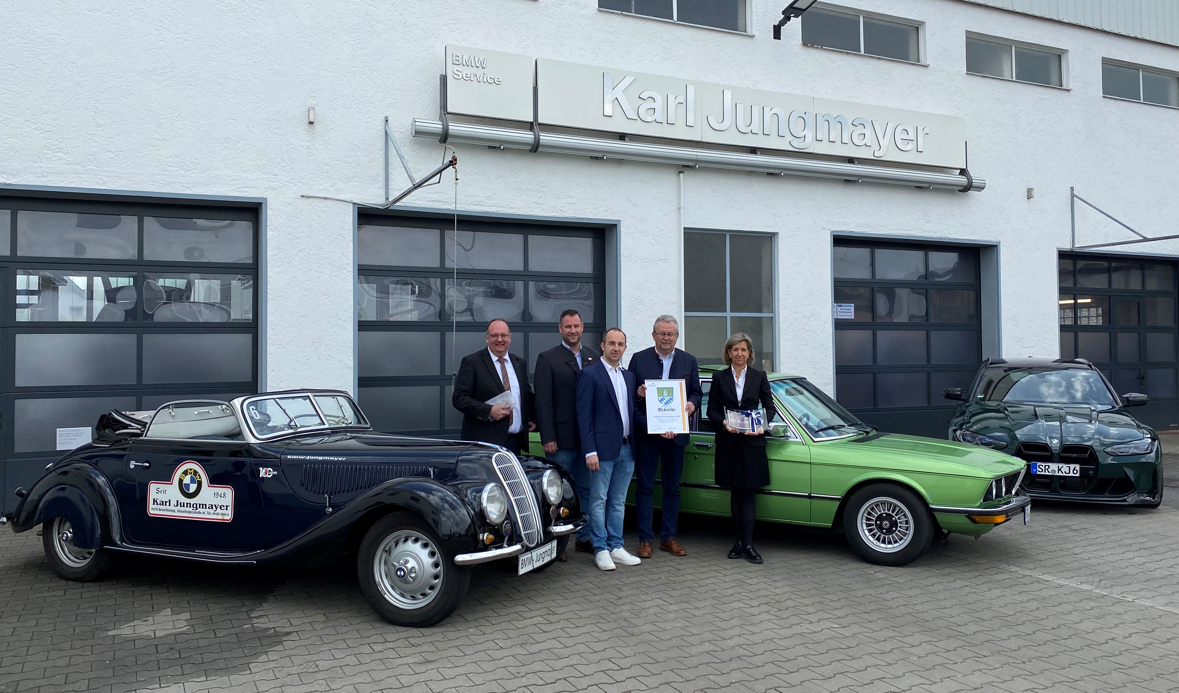 Geiselhörings Bürgermeister Herbert Lichtinger, Wirtschaftsreferent Martin Köck, Karl Jungmayer, Landrat Josef Laumer und Gudrun Jungmayer  beim Gratulationsbesuch mit Autos aus drei Generationen.