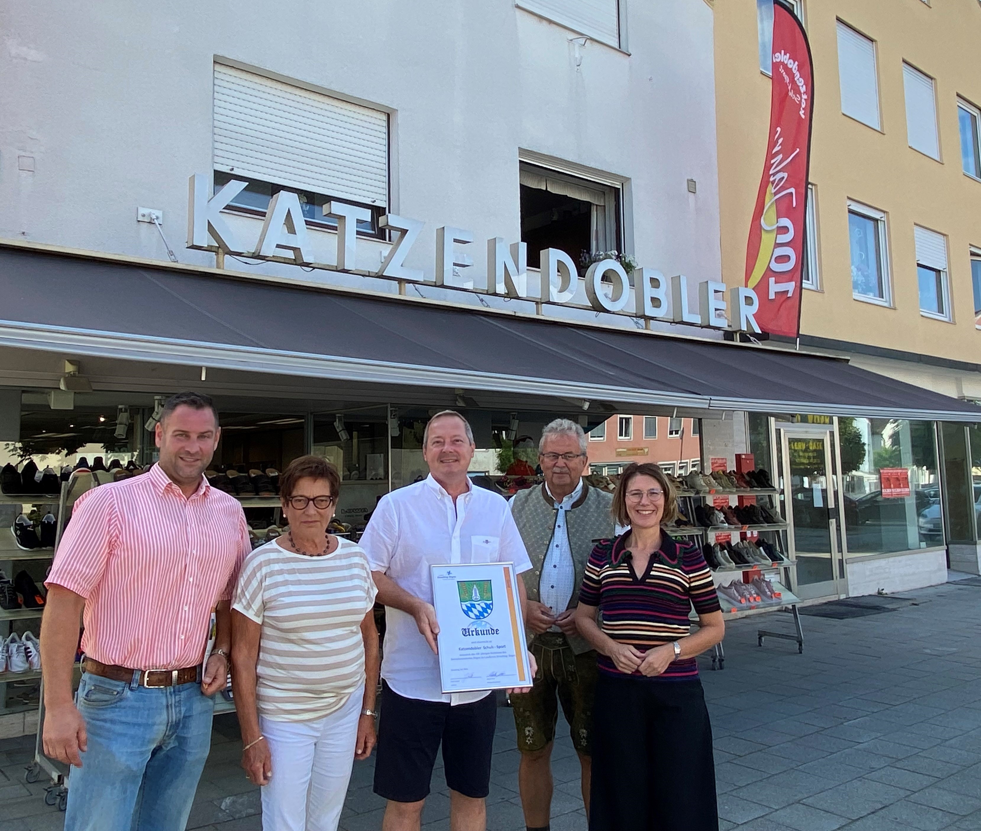 100 Jahre Katzendobler.jpg Martin Köck (Wirtschaftsreferent), Annemarie Katzendobler, Florian Katzendobler, Landrat Josef Laumer und Bürgermeisterin Andreas Probst stehen vor dem Geschäft am Bogener Stadtplatz.