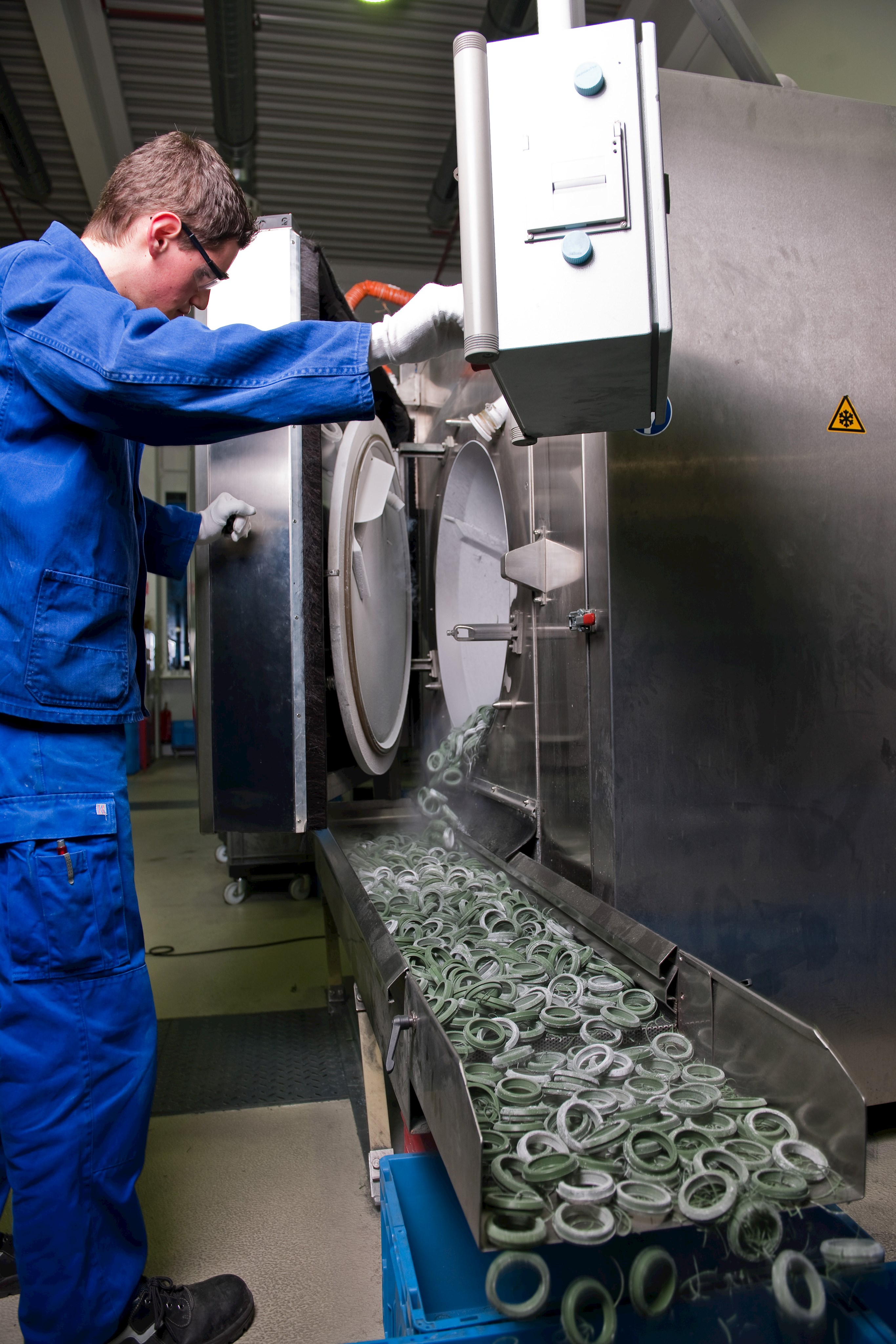 Ein Mitarbeiter öffnet eine Maschine, in der Dichtringe durch Kälte behandelt wurden.