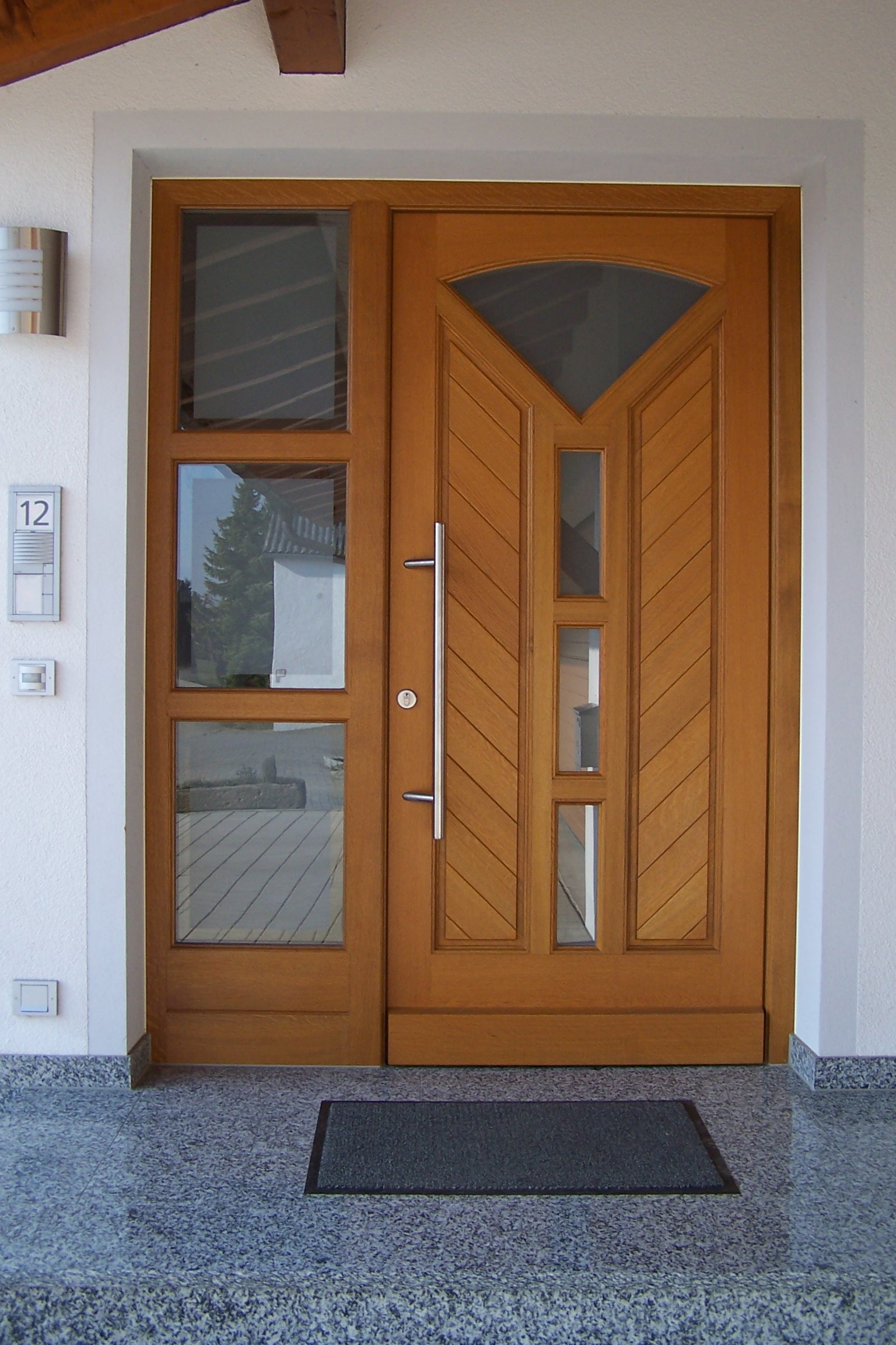 Haustüre aus Holz mit Fensterelementen und einem Seitenteil links mit drei Fenstern