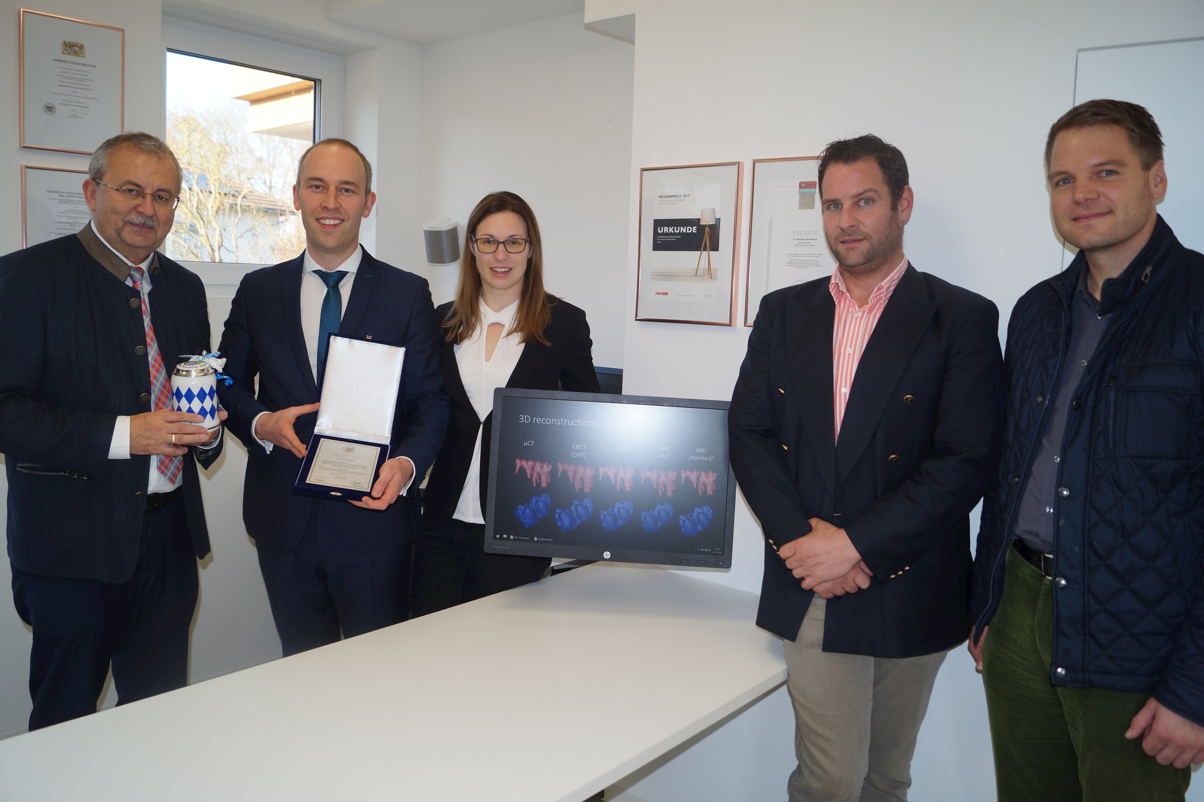 Landrat Josef Laumer überreicht Dr. Andreas Detterbeck, der den FEO-Award 2018 in der Hand hält, und seiner Frau Amelie ein Erinnerungsgeschenk. Mit im Bild auch Wirtschaftsreferent Martin Köck und Christoph Paukner, Geschäftsleitender Beamter der Stadt Bogen (von links). Auf dem Computer auf dem Bild sind Teile der Forschung von Dr. Detterbeck zu sehen.