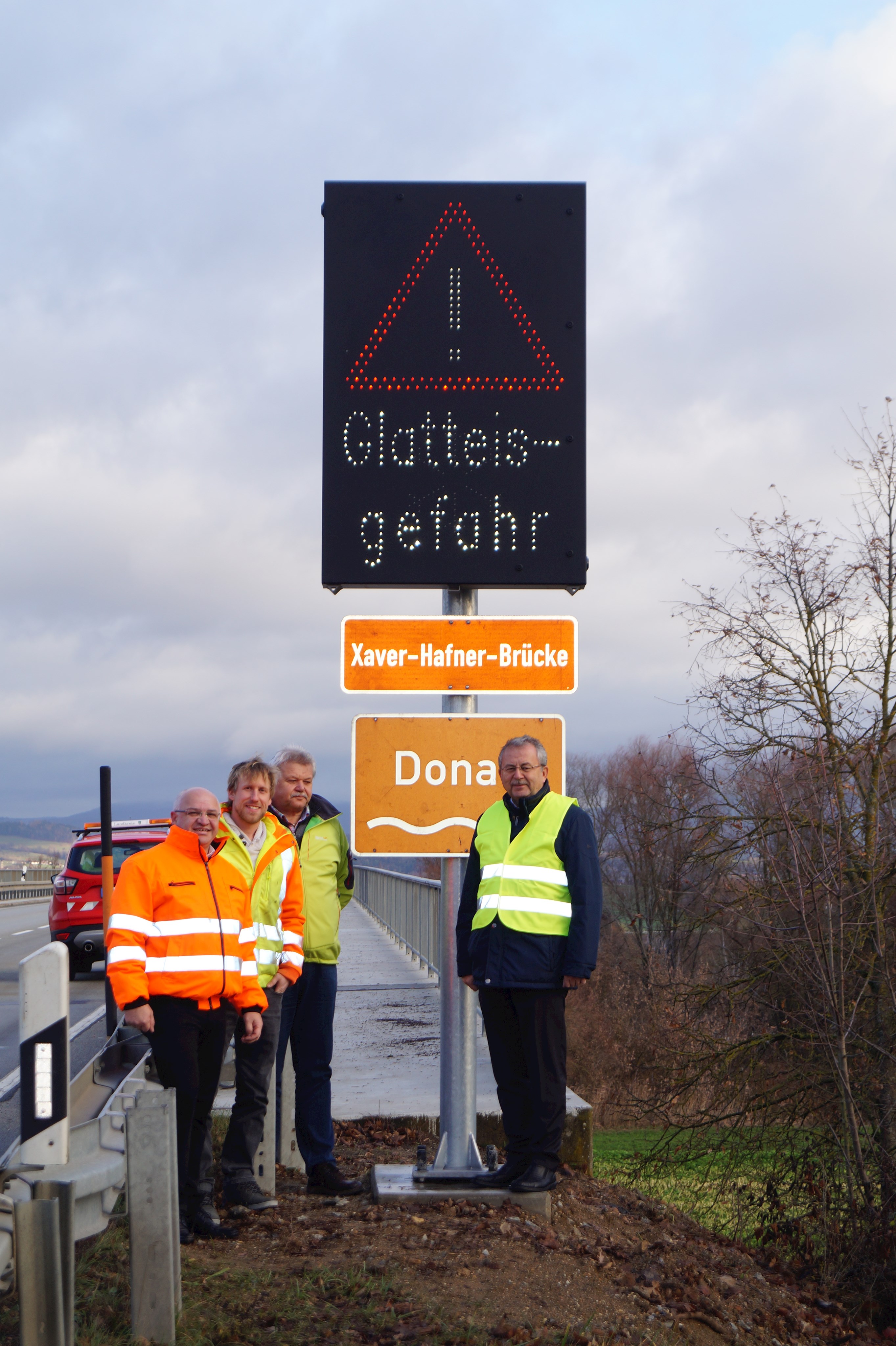 Markus Fischer (Leiter der Tiefbauverwaltung), Thomas Schedlbauer (Tiefbauverwaltung), Eugen Schedlbauer (Leiter des Bauhofs Ittling) und Landrat Josef Laumer (von links) besichtigen die neue Wechselverkehrszeichenanlage auf der Xaver-Hafner-Brücke bei Bogen.