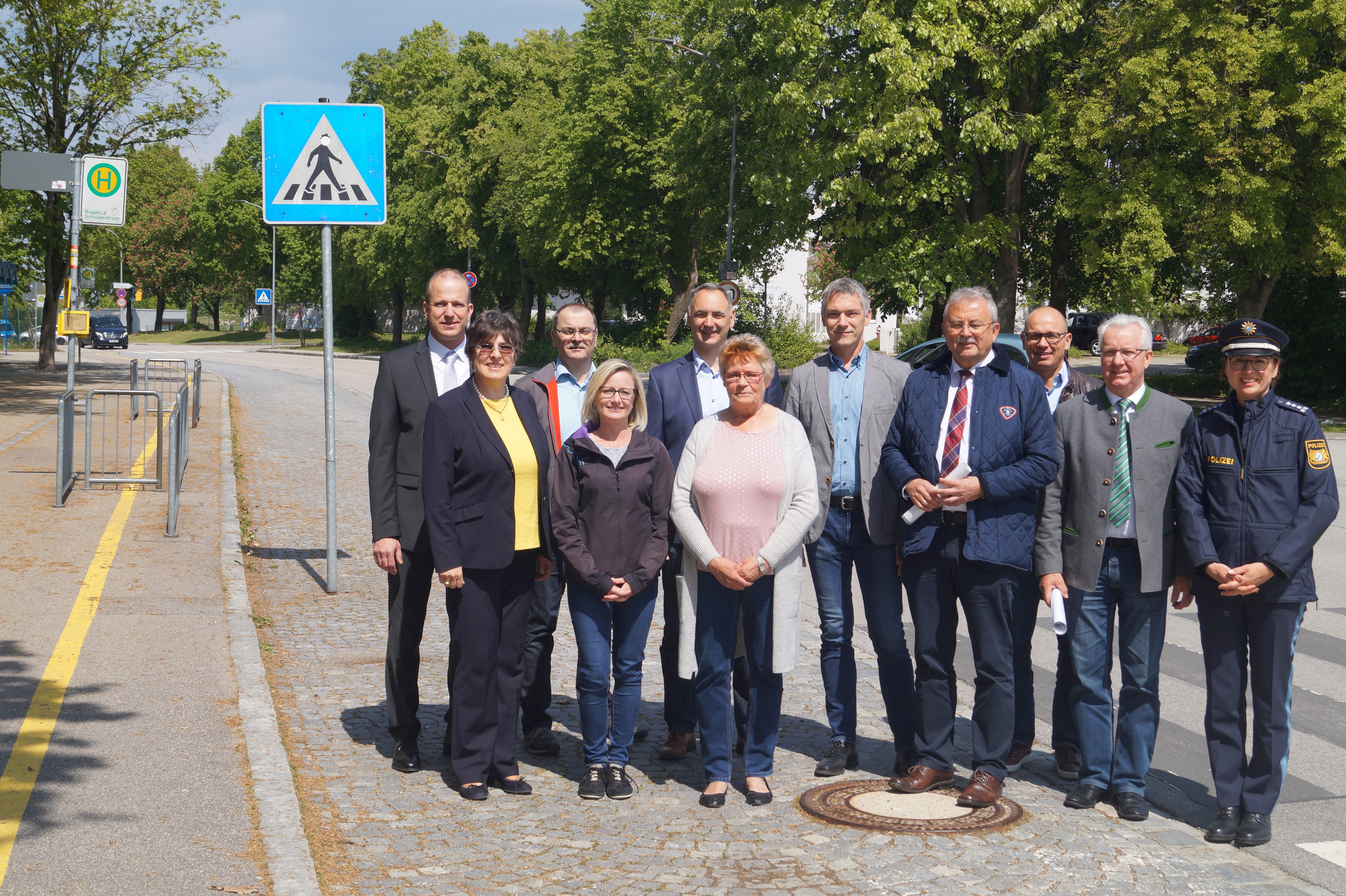 Die beiden neuen Busaufsichten Iris Hübscher und Waltraud Franke (vorne, zweite und dritte von links) am Schulzentrum Bogen vor einem Bushäuschen und dem Zebrastreifen gemeinsam mit OstD Clemens Kink (Schulleiter Veit-Höser-Gymnasium), Rita Kienberger (Sachgebietsleiterin Verkehrswesen am Landratsamt Straubing-Bogen), Richard Vaith (Sachbearbeiter ÖPNV am Landratsamt Straubing-Bogen), Rektor Stefan Nagl (Herzog-Ludwig-Mittelschule), Stellvertretender Realschulrektor Alexander Reimer (Ludmilla-Realschule), Landrat Josef Laumer, Helmut Winklmeier (Stadt Bogen), Bogens Bürgermeister Franz Schedlbauer und Daniel Neumayer (Leiterin der PI Bogen, von links).