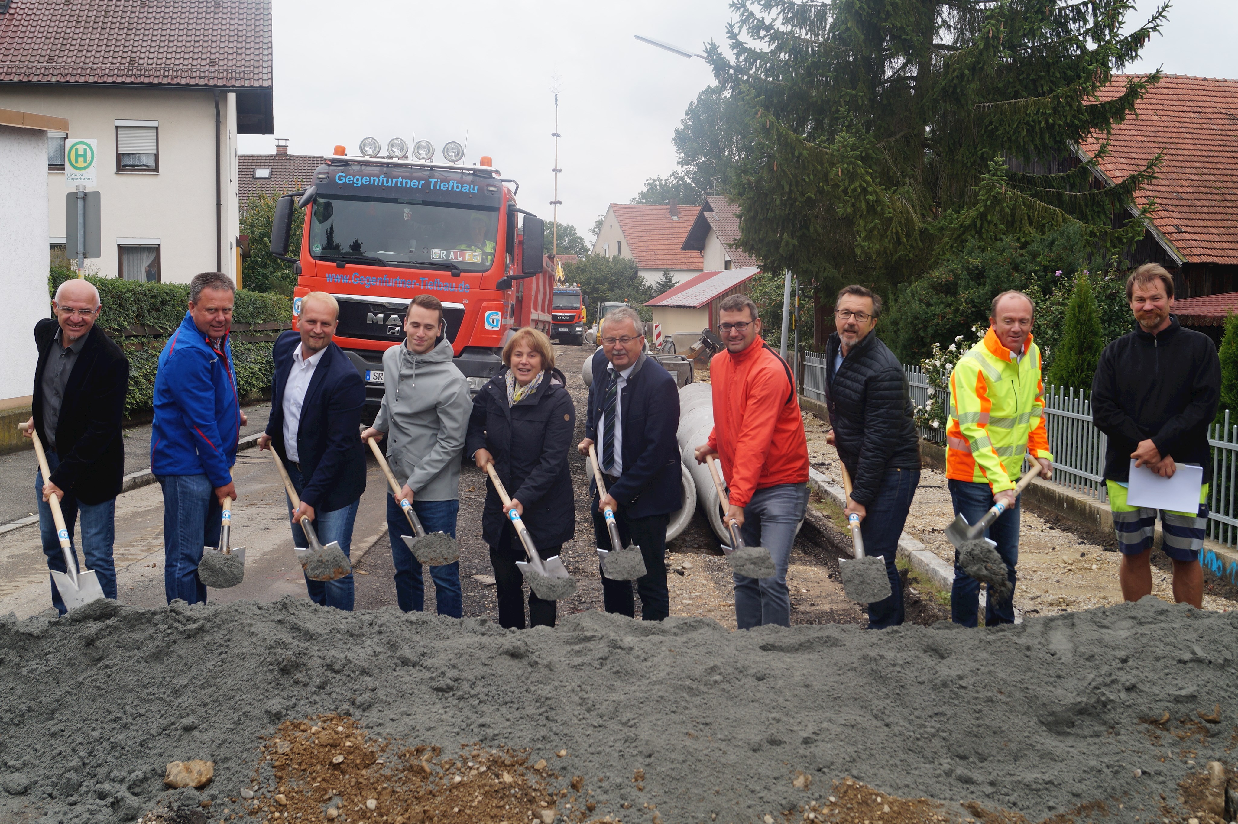 Spatenstich an der Baustelle in Opperkofen mit Spaten und Lastwagen im Hintergrund.