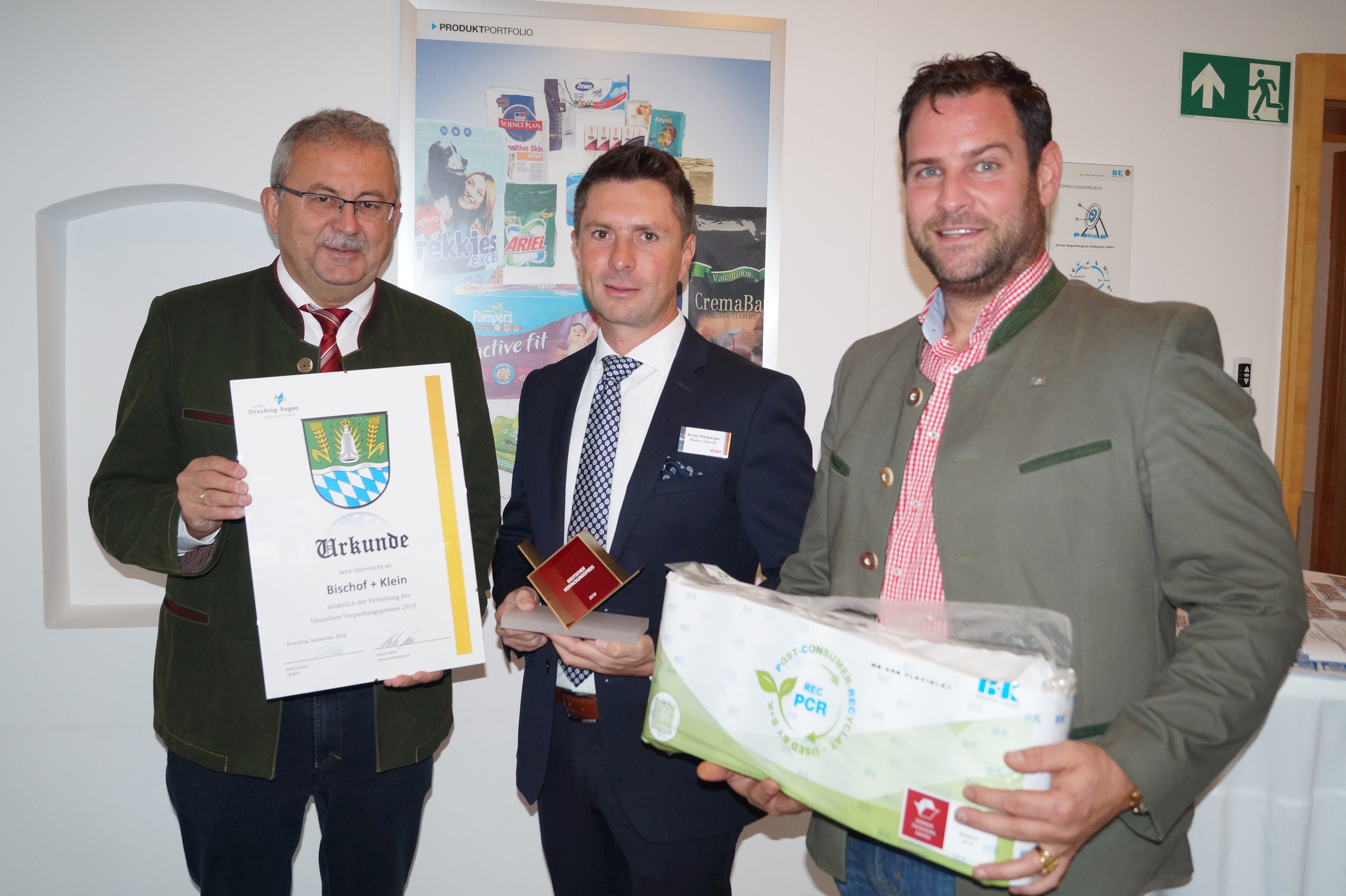 Landrat Josef Laumer gratuliert im Namen des Landkreises mit einer Urkunde zum Deutschen Verpackungspreis 2019, den Werksleiter Armin Kienberger in Händen hält. Wirtschaftsreferent Martin Köck (von links) präsentiert das Produkt, das die Auszeichnung erhalten hat.