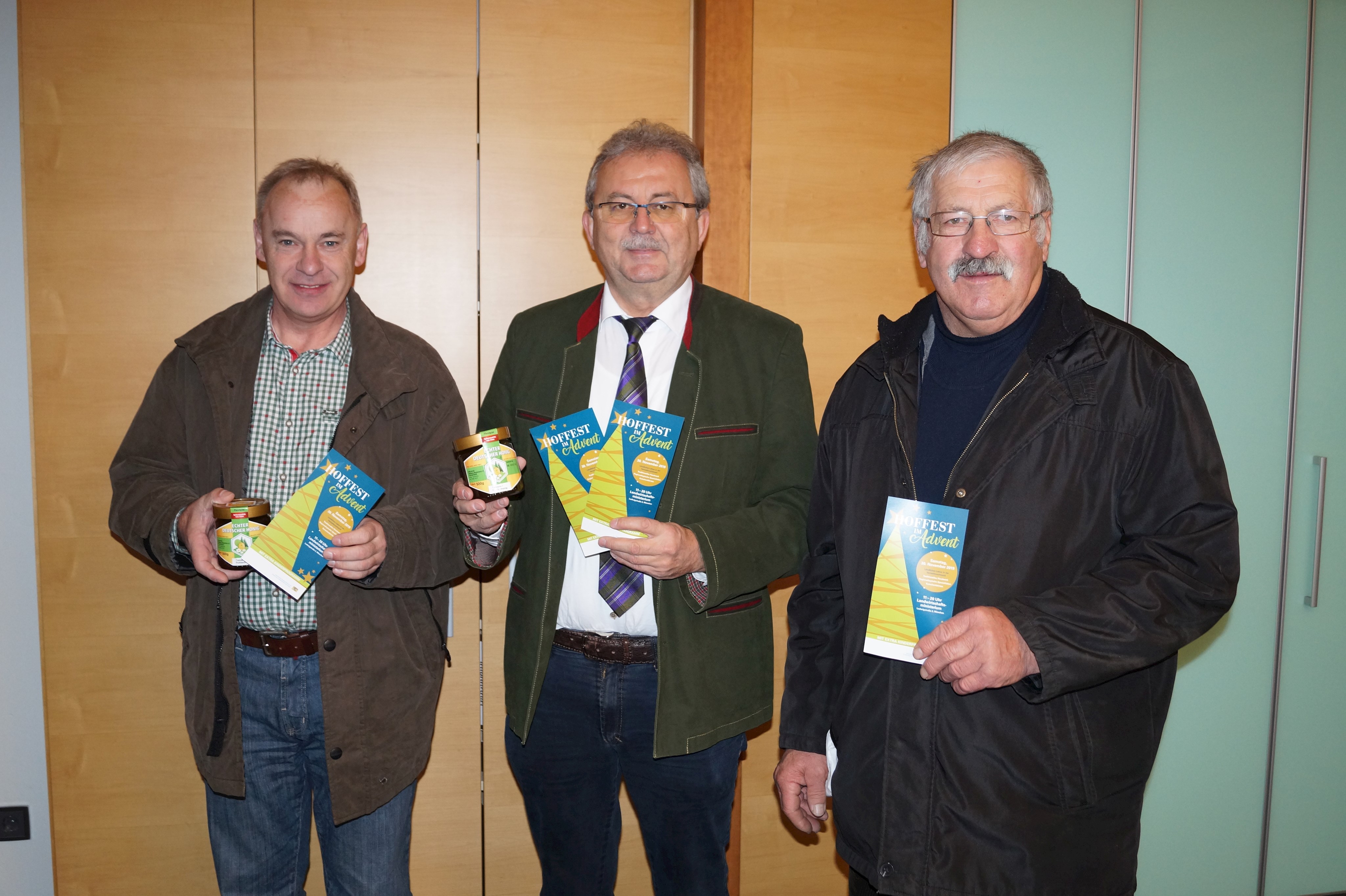 Erwin Spranger (Imkerverein Steinburg-Neukirchen), Landrat Josef Laumer und Josef Brem (Vorsitzender Imkerverein Steinburg-Neukirchen, von links) präsentieren stehend im Büro des Landrats den Honig und das Programm des Hoffestes.